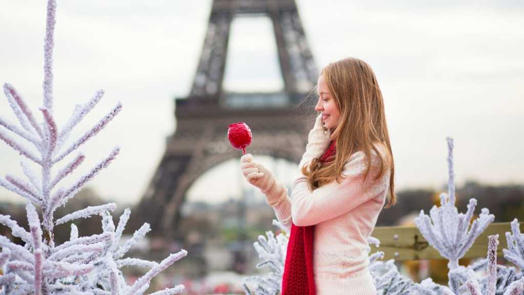 Une Parisienne mange une "pomme d'amour" sur un marché de Noël à Paris.
